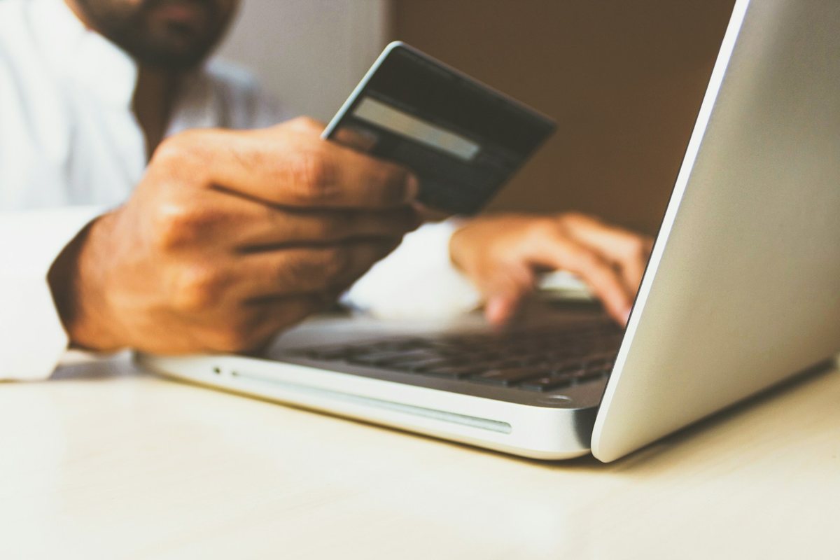 Dizüstü bilgisayar başında kredi kartıyla online ödeme yapan kişi