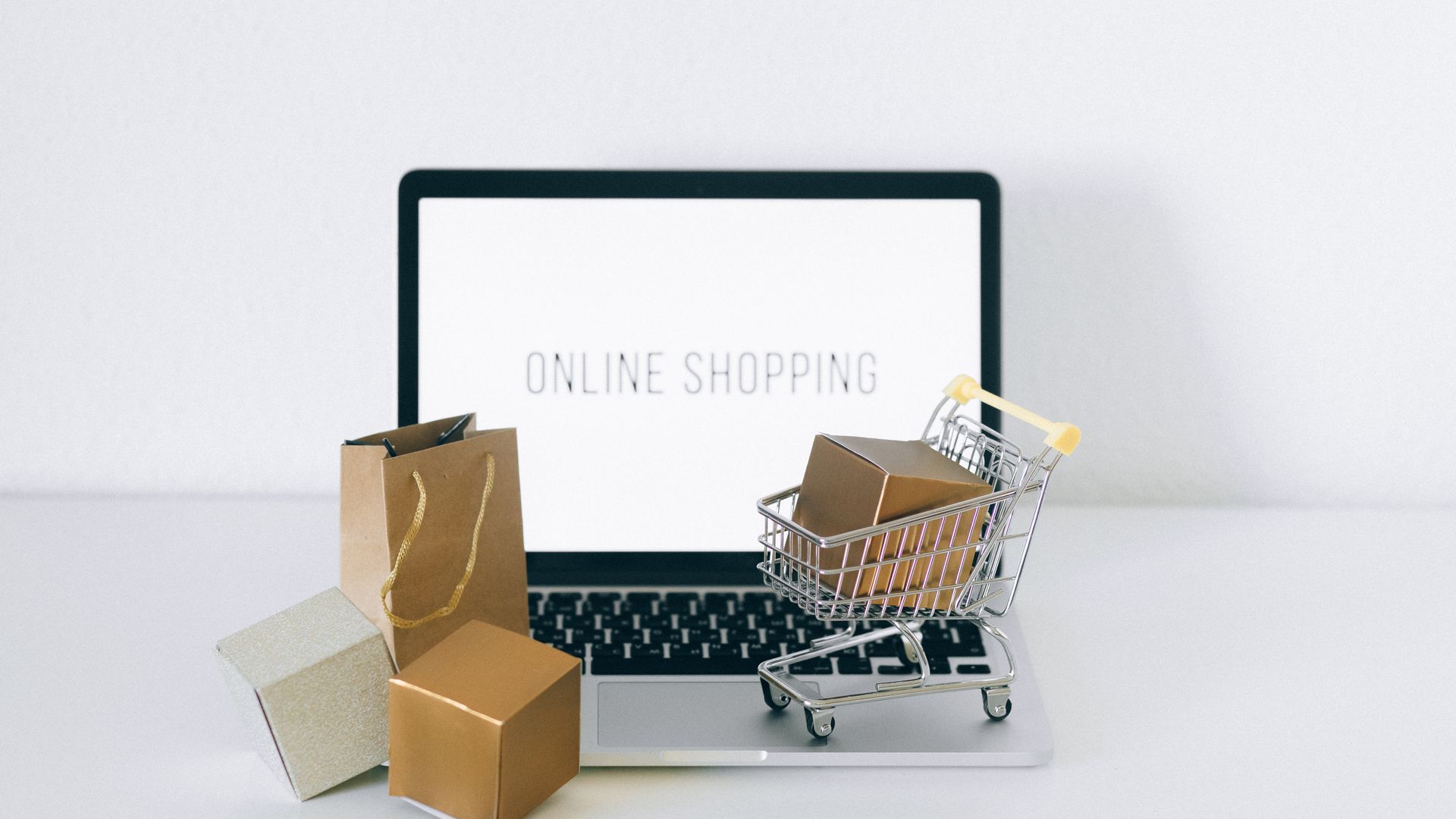 Dizüstü bilgisayar, alışveriş sepeti ve kargo kutularıyla e-ticaret sitesi kurulumu